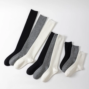 Detail view of knitted argyle knee-high and mid-calf socks in black, grey, and white tones