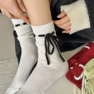 Nahaufnahme weißer Strickstrümpfe mit schwarzer Plüschschleife und saisonalen Farben