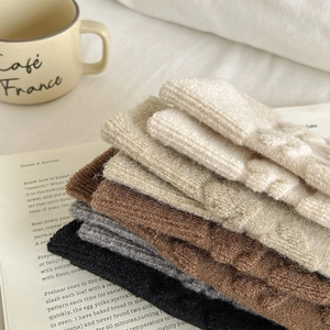 Close-up of thick knitted wool socks in earthy tones stacked on a vintage book