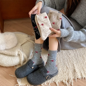 Detail of wool socks showing cute bear embroidery and heart patterns in various colors