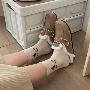 Close-up of cozy brown suede slippers with white faux shearling lining on wooden floor