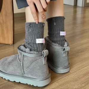 Detail of dark grey ribbed socks with distressed holes and woven label over snow boots