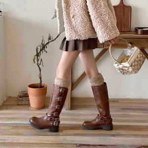 Detail of vintage brown leather tall boots with metal buckles and warm winter layering