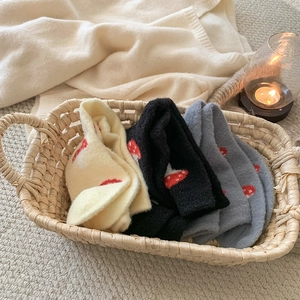 Cozy plush socks with red mushroom pattern in a straw basket for autumn and winter
