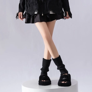 Detail of black ribbed knit leg warmers paired with fuzzy platform sandals in a minimalist style