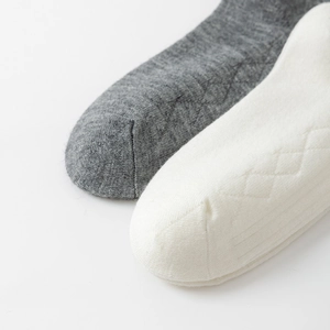 Detail view of knitted mid-calf socks with textured diamond pattern and fine stitching