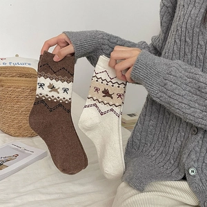 Dettaglio di calze in misto lana con jacquard a cagnolino e fiocchi in un ambiente invernale