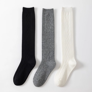 Three pairs of knit knee-high socks in black, grey, and cream with diamond pattern
