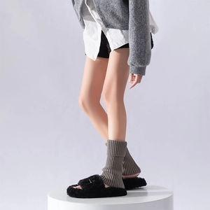 Detail view of dark grey knitted leg warmers with black faux fur slippers for winter style