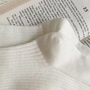 Detail of white ribbed knit cashmere socks with cotton texture on an open book