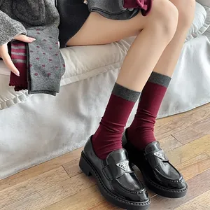 Close-up of vintage burgundy crew socks with gray bow patterns and ribbed cuffs style