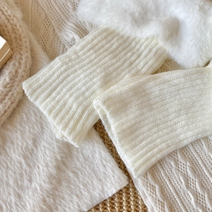 Detail of cream cable knit leg warmers featuring fluffy faux fur trim and ribbed texture