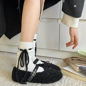 Detail von plüschigen schwarzen Mary Jane Schuhen mit Schleifen und weißen Socken