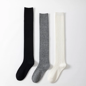 Detail of three pairs of knee-high socks in black, grey and white with diamond knit texture
