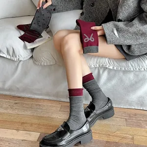 Close-up of vintage burgundy bow socks with grey stripes and polka dots on a sofa