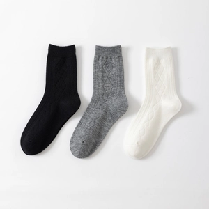 Detail of knit socks with diamond texture and ribbed cuffs in black grey and white