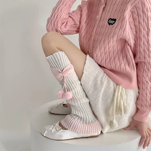 Détail de jambières Lolita rose et blanc avec nœuds et décorations de pompons en peluche