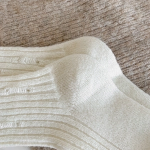 Detailed close-up of thick beige ribbed knit cashmere socks with soft fuzzy texture