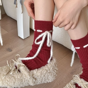 Detail von roten Strickkanten mit weißen Plüschschleifen und dekorativen Nähten