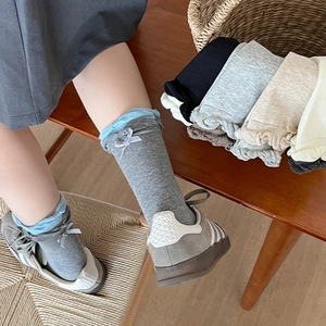 Close-up of color-block crew socks with lace trim and delicate bow accent detail