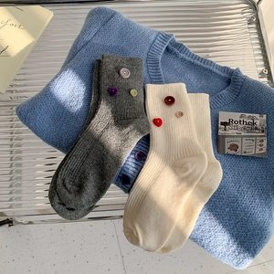 Detail of ribbed knit socks with decorative buttons and red heart patches