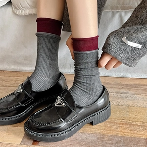 Close-up of black patent leather loafers with vintage ribbed socks and burgundy details