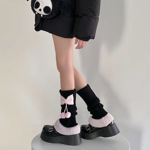 Gros plan de jambières Lolita noires avec nœuds roses et pompons décoratifs
