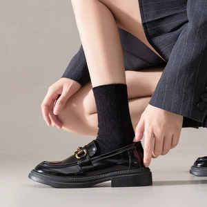 Black patent leather loafers with gold horsebit and thick rubber soles in preppy style