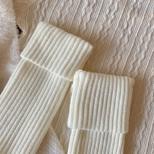 Detailed close-up of ribbed knit leg warmers in off-white featuring thick folded cuffs
