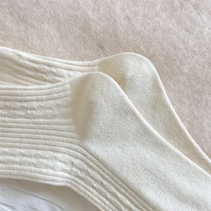 Close-up of cream knit socks showing vertical stripes and cable patterns for winter warmth