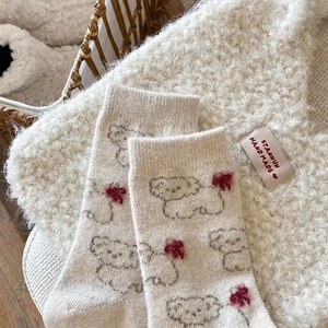 Close-up of thick beige wool socks with cute cartoon puppy pattern and soft warm texture