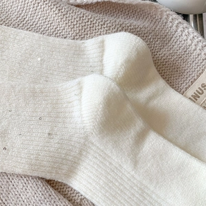Detailed macro view of white wool knit socks with sparkling silver sequins and ribbed cuffs