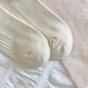 Detail of cream white knit knee-high socks with vertical stripes and soft cashmere texture