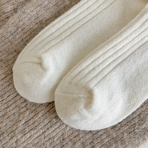 Close-up of cream white cashmere socks showing vertical knit texture and toe stitching