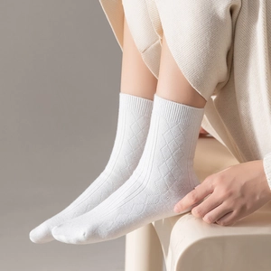 Detailed knit texture of white calf-length socks with elegant diamond pattern