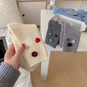 Detail of ribbed knit leg warmers with colorful decorative buttons in various soft tones