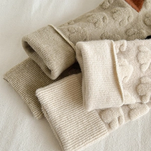 Close-up of thick wool socks featuring 3D floral relief knit and warm winter texture