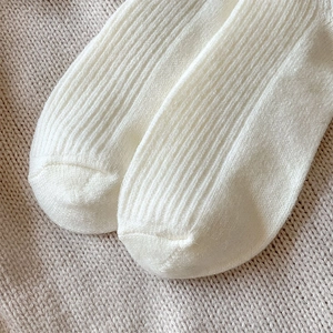 Close-up of white wool socks showing premium rib knit texture and seamless toe stitching