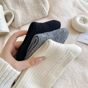 Detailed view of thick vertical stripe knit socks in black, grey, and cream colors