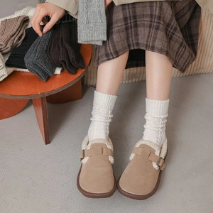 Detail of camel suede clogs with warm fleece lining and cable knit socks in a home setting
