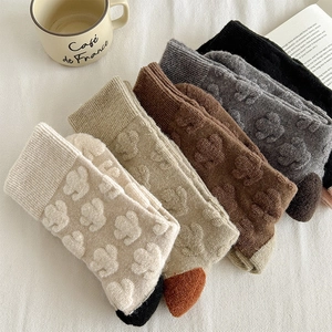 Detail of five pairs of wool blend socks with 3D embossed floral patterns in earthy tones