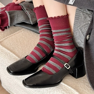 Detail of vintage burgundy striped socks with lace trim paired with matte Mary Janes