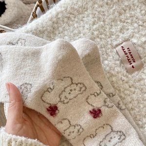 Close-up of cream knit wool socks featuring cute dog pattern and red heart details