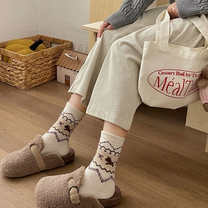 Dettaglio di calze di lana a maglia con jacquard di cucciolo marrone e fiocchi rossi