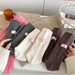Detailed close-up of thick ribbed knit socks with distressed holes and handmade label
