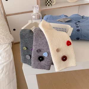Detail of ribbed knit crew socks with decorative buttons in gray and cream white colors