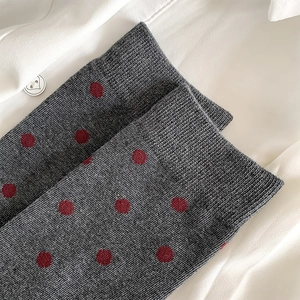 Detail of dark grey knit socks with vintage burgundy polka dots on white fabric