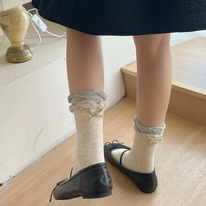 Detailed view of cream ruffled socks with small yellow ribbons and black ballet flats