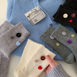 Detail of ribbed knit crew socks featuring vintage velvet buttons in various colors