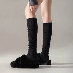 Détail de chaussettes montantes en tricot noir avec texture plissée et pantoufles douces